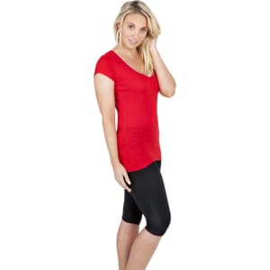 A woman wearing a red V-neck T-shirt paired with black capri leggings, standing against a white background.