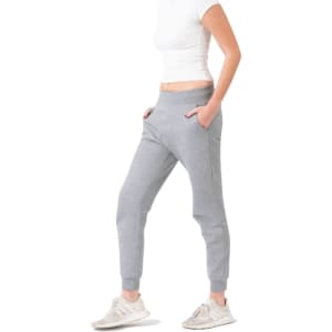 Grey women's track pants with a slim fit and pockets, paired with a fitted white top and shoes.