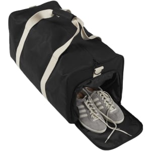 A black duffle bag with a zipper, featuring a pair of grey and white sneakers peeking out from the side compartment.