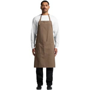 A brown canvas apron worn by a model, featuring a front pocket and adjustable neck straps.