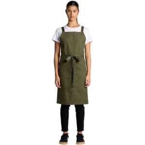 An olive green apron with a waist tie and pockets, worn over a white t-shirt and black pants.