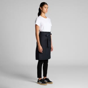 A dark navy half apron with a waist tie, worn over a white t-shirt and black pants.