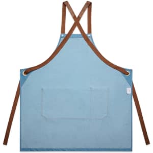 A denim apron in light blue with brown straps and a front pocket, featuring a small logo.