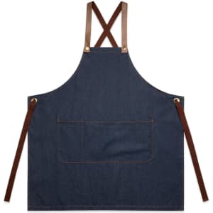 A denim apron with brown leather straps and a front pocket, featuring a logo.