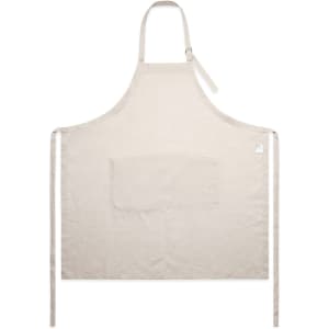 A beige linen apron featuring a front pocket and ties for securing. Includes a logo on the side.