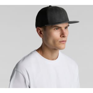 A grey faded trucker cap with a flat brim, featuring a logo, worn by a model in a white t-shirt.