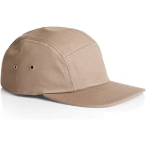 A tan five-panel cap featuring eyelets for ventilation and a curved brim, with a logo on the side.
