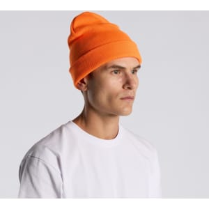 An orange beanie worn by a model, featuring a snug fit and a prominent rolled cuff.