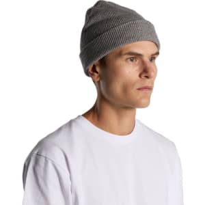 A grey knit beanie worn by a model, featuring a ribbed texture and a close-fitting design.