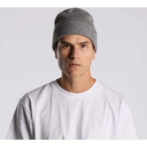 A grey knit beanie being worn by a model in a plain white T-shirt against a neutral background.