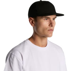 A black cotton cap with a flat brim, worn by a person in a white T-shirt, featuring a logo.