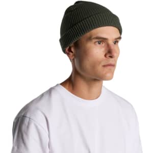 A green ribbed beanie worn by a man, featuring a snug fit and a logo on the side.