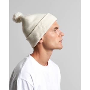 A white pom pom beanie worn by a man, featuring a ribbed edge and a fluffy pom pom on top.