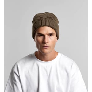 A beanie in a muted brown colour, worn by a model, featuring ribbed texture and a logo.