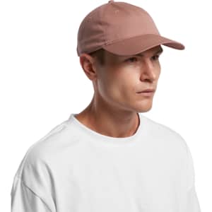 A cap in a soft pink colour, featuring a curved visor and a rear adjustment strap. It has a logo on the side.