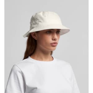 A white bucket hat with ventilation eyelets, worn by a person in a plain white t-shirt.