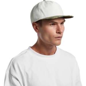 A two-tone camo cap with a white body and a camo-patterned brim, worn by a model in a plain white shirt.