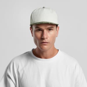 A man wearing a two-tone camouflage cap in white and green, paired with a plain white T-shirt.