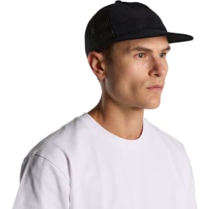 A man wearing a black trucker cap with a mesh back, paired with a white T-shirt. The cap features a logo.