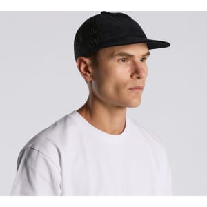 A black trucker cap with a mesh back, worn by a model in a white T-shirt. The cap features a logo.