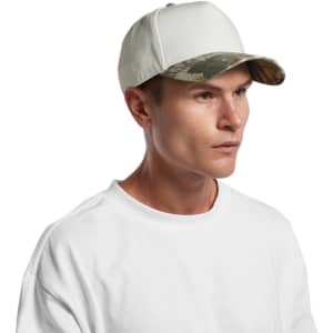 A white cap with a camo-patterned peak, featuring a logo on the front, worn by a model.