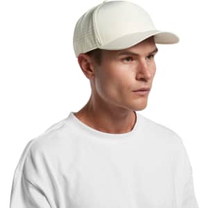 A white perforated cap displayed on a model, featuring a solid front panel and a logo on the side.