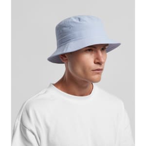 A man wearing a light blue nylon bucket hat, featuring a subtle logo, against a plain background.