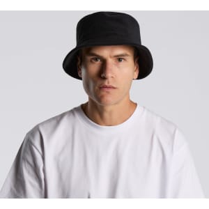 A black Terry Bucket Hat displayed on a model wearing a white t-shirt. The hat features a logo.