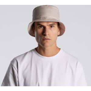 A light beige bucket hat with a wide brim, featuring a simple design and a logo.