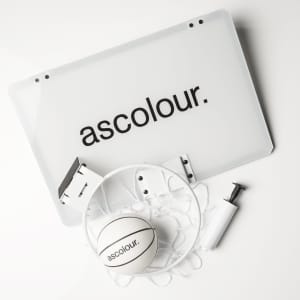 A mini basketball set featuring a white backboard, a basketball, a pump, and hardware for mounting, all with branding.
