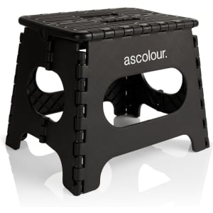 A black utility stool with a textured top and cut-out sides, featuring a logo on one side.