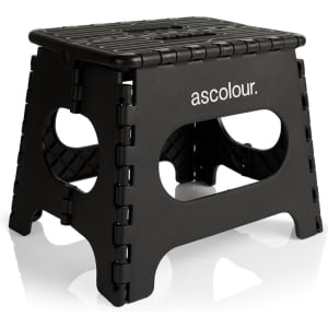 A black utility stool with a textured surface and cut-out handles, featuring a brand logo.