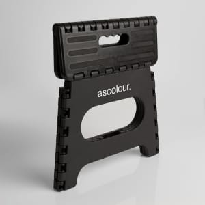 A black folding stool with a textured surface and a handle, featuring a logo on the front.