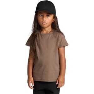 A child wearing a brown staple T-shirt and a black cap, standing with a neutral expression.