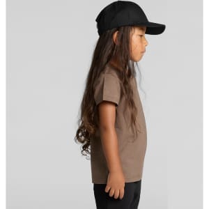 A child wearing a brown staple tee and a black cap, shown in profile against a plain background.