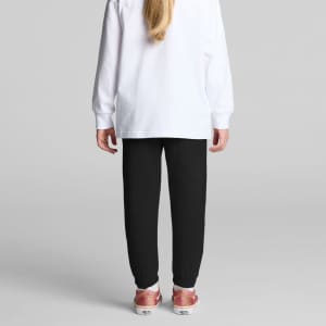 Black track pants for kids, featuring a tapered fit and cuffed ankles, paired with a white long-sleeve top.