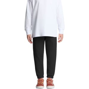 Black track pants for kids, featuring an elastic waistband and cuffs, paired with a white long-sleeve top and casual shoes.