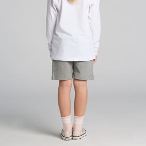 Kids stadium shorts in grey, featuring a simple design. Worn with a long-sleeve white top and patterned socks.