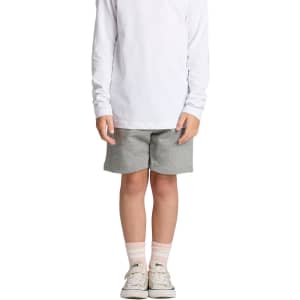 Grey sports shorts for kids, paired with a long white top and light-coloured shoes, featuring a logo.