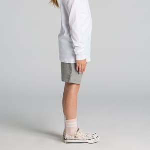 Kids stadium shorts in light grey, paired with a long-sleeve white top and patterned sneakers.