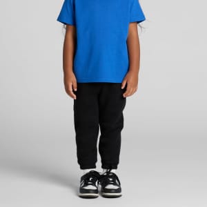 Black track pants with cuffed hems, paired with a blue t-shirt and black sneakers. Features a logo on the pants.