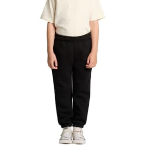 Black youth track pants with elastic waistband, paired with a light-coloured t-shirt and white sneakers.