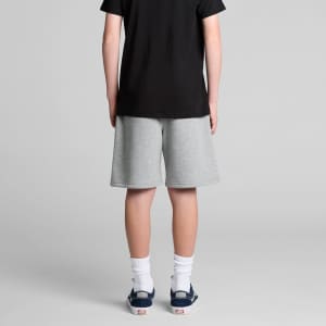 A pair of grey track shorts, featuring a relaxed fit, seen from behind on a wearing person. The person is dressed in a black shirt.