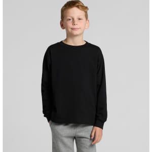 A child wearing a black long-sleeve T-shirt, paired with grey trousers, posing against a plain background.