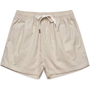 Light beige shorts with an elastic waistband and drawstring detail. Features a logo on the waistband.