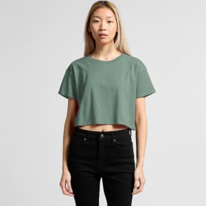A cropped tee in a muted green colour, featuring a relaxed fit and paired with black jeans. The shirt has branding.