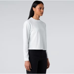 A long-sleeve white t-shirt displayed on a model, featuring a simple design and round neckline.