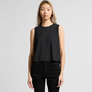 A black crop tank top with a relaxed fit, featuring a logo on the front. Model is wearing black jeans.