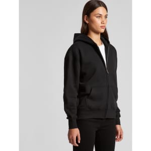 A black zip-up hoodie worn by a model, featuring a hood and front pockets. The hoodie has a logo.