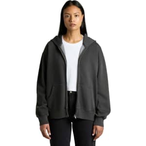 A woman wearing a faded dark grey zip hoodie, featuring a front pocket and a logo.